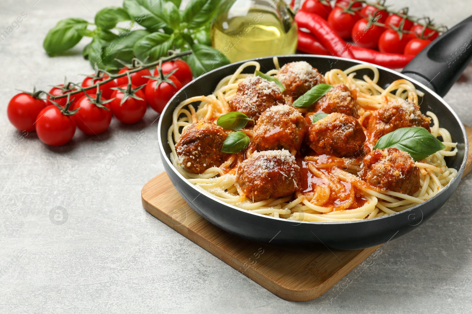 Photo of Delicious pasta with meatballs and ingredients on light grey table, closeup