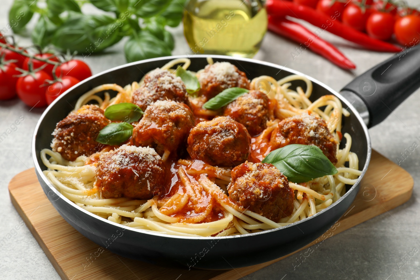 Photo of Delicious pasta with meatballs and ingredients on light grey table, closeup