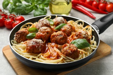 Photo of Delicious pasta with meatballs and ingredients on light grey table, closeup