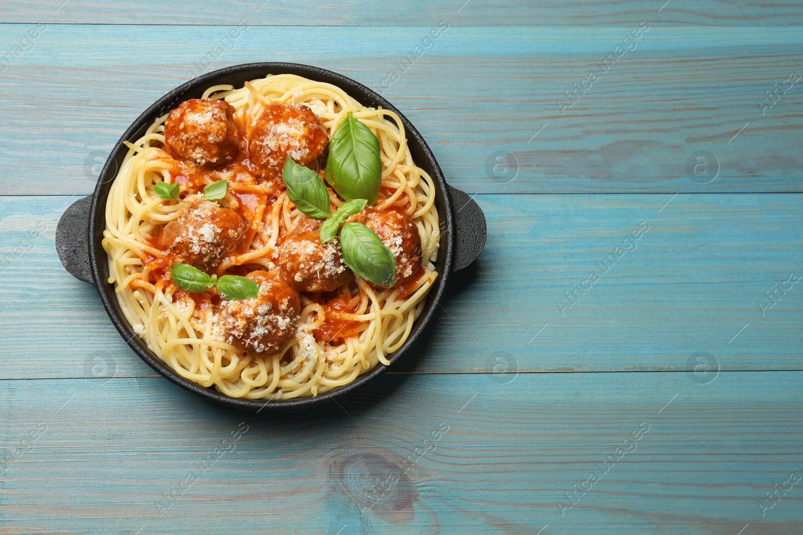 Photo of Delicious pasta with meatballs on light blue wooden table, top view. Space for text