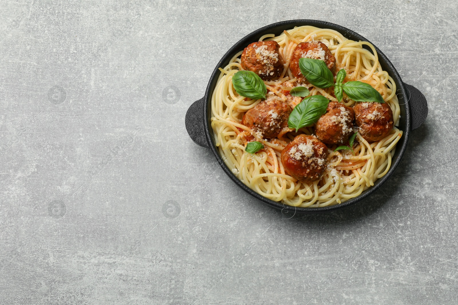 Photo of Delicious pasta with meatballs on light grey table, top view. Space for text