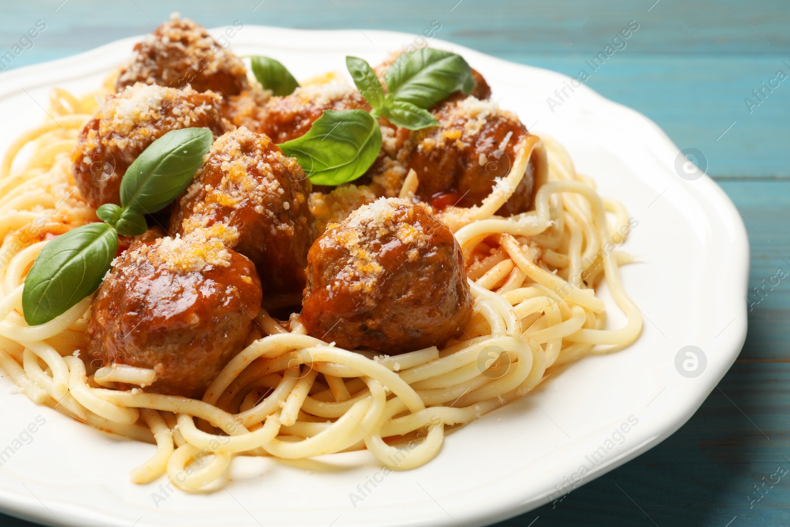 Photo of Delicious pasta with meatballs on light blue wooden table, closeup