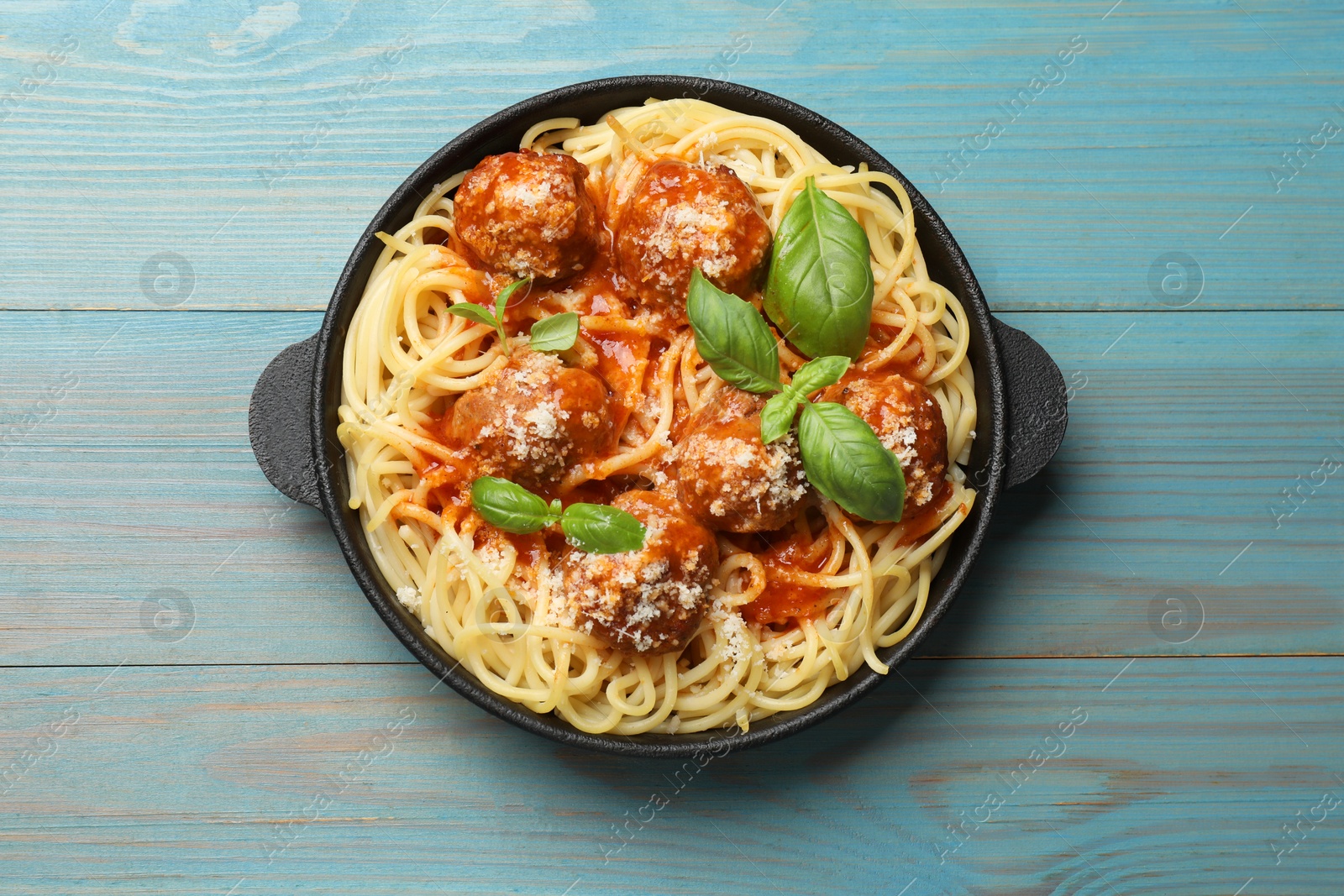 Photo of Delicious pasta with meatballs on light blue wooden table, top view