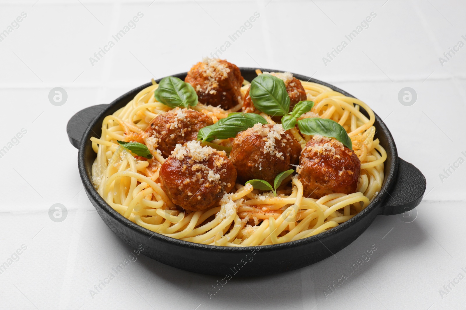 Photo of Delicious pasta with meatballs on white tiled table, closeup