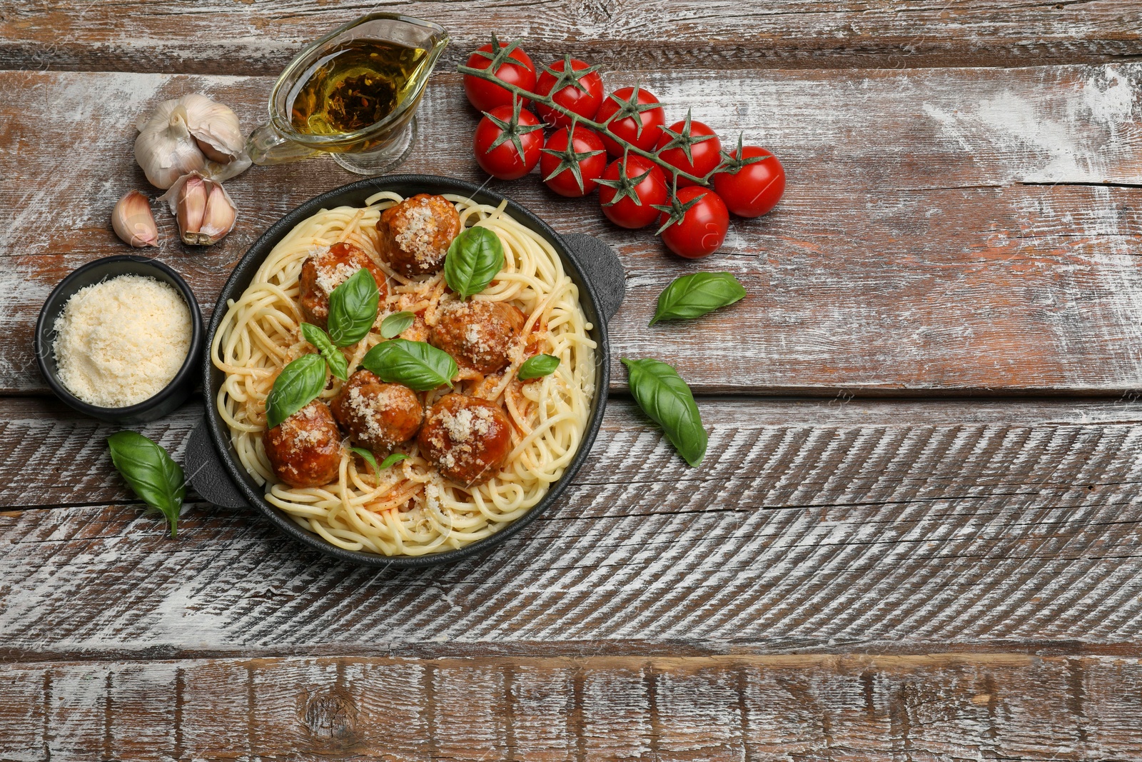 Photo of Delicious pasta with meatballs and ingredients on wooden table, flat lay. Space for text