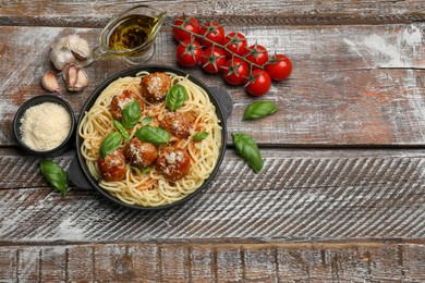 Delicious pasta with meatballs and ingredients on wooden table, flat lay. Space for text