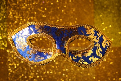 Beautiful carnival mask against blurred golden background, closeup