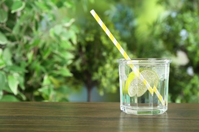 Photo of Glass of soda water with lime on wooden table against blurred background. Space for text