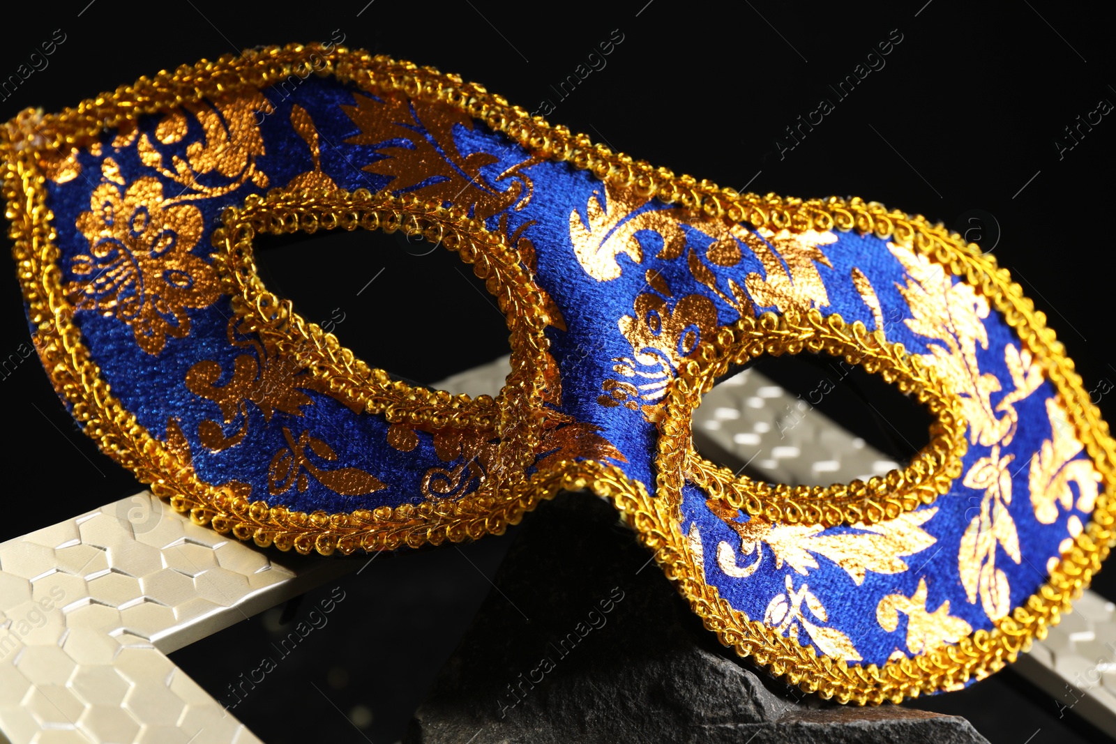 Photo of Beautiful carnival mask on dark background, closeup