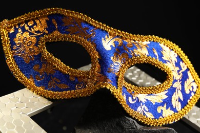 Photo of Beautiful carnival mask on dark background, closeup