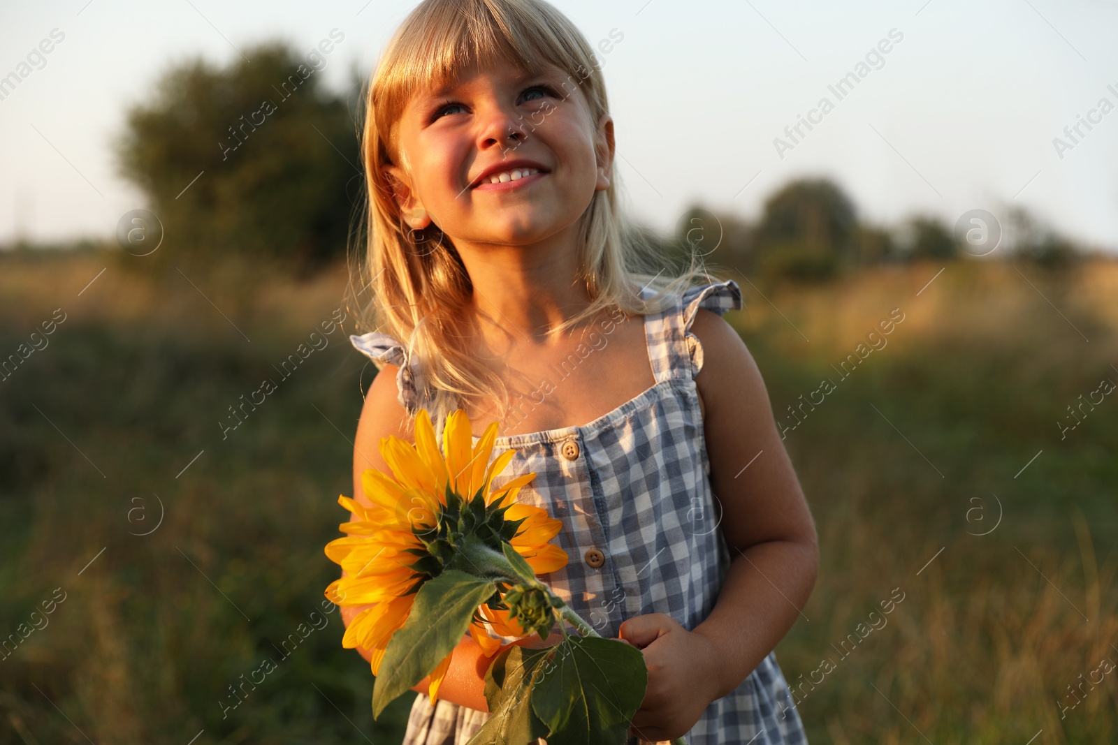 Photo of Little girl with sunflower at meadow. Child enjoying beautiful nature