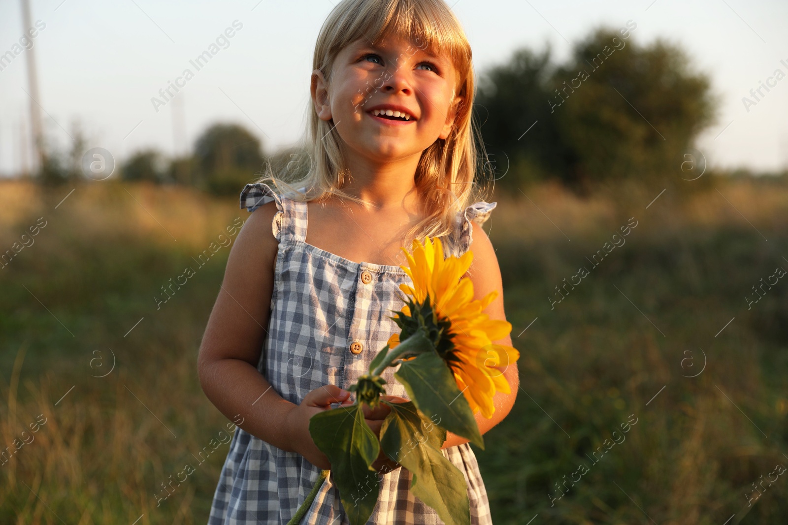 Photo of Little girl with sunflower at meadow. Child enjoying beautiful nature