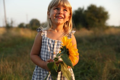 Photo of Little girl with sunflower at meadow. Child enjoying beautiful nature