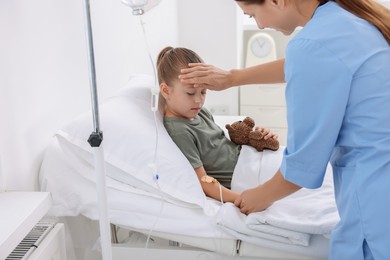 Photo of Doctor examining little girl on bed at hospital