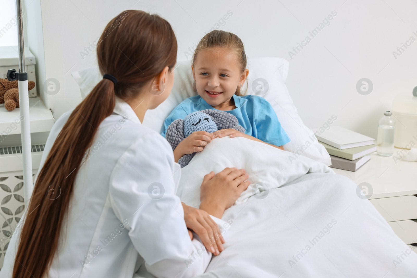 Photo of Doctor examining little girl on bed at hospital