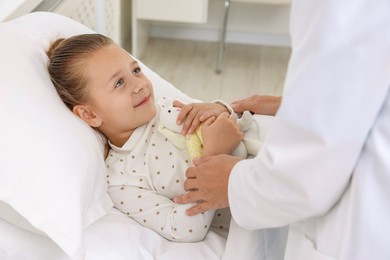 Photo of Doctor examining little girl on bed at hospital, closeup