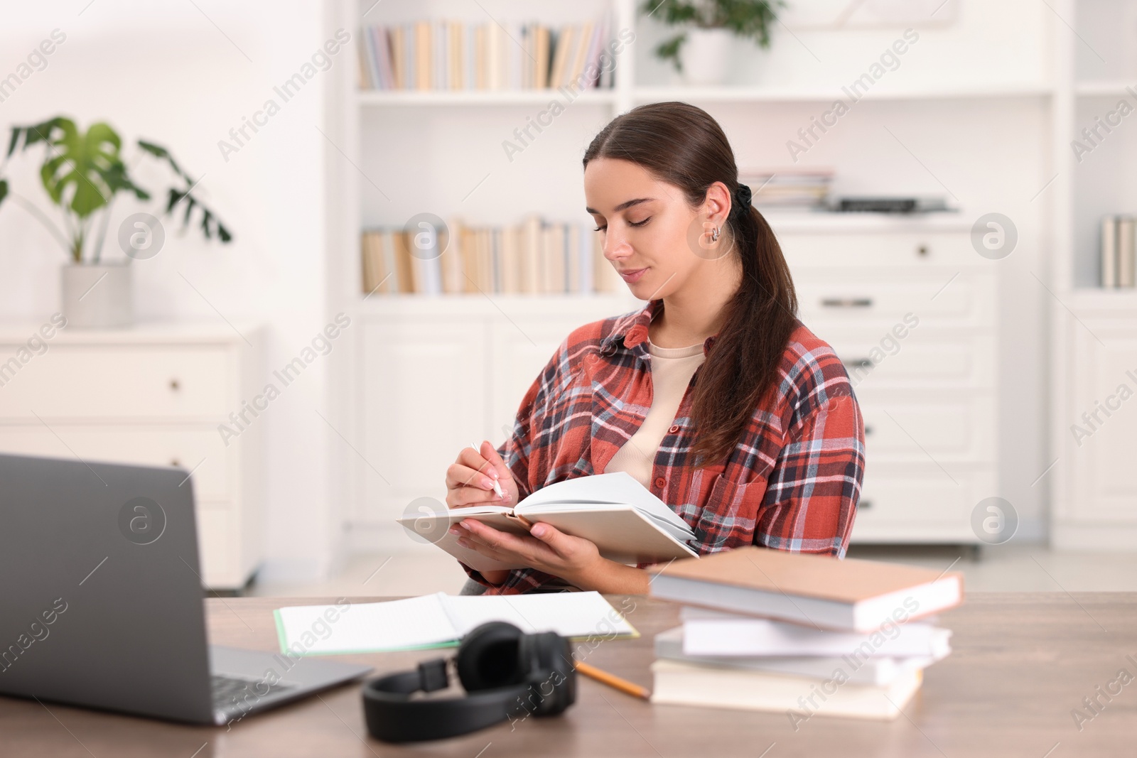 Photo of Student taking notes while studying at table indoors