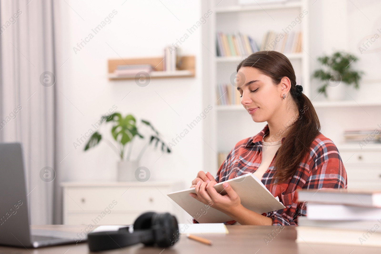 Photo of Student taking notes while studying at table indoors