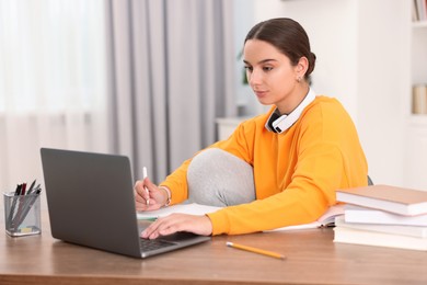 Photo of Student studying with laptop at wooden table indoors