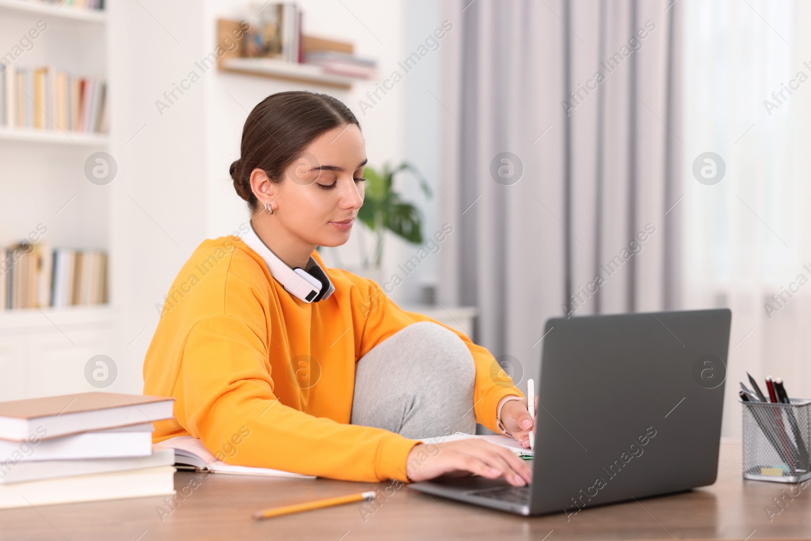 Photo of Student studying with laptop at wooden table indoors