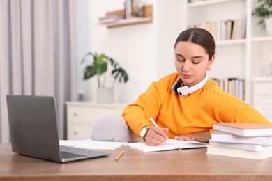 Photo of Student with headphones studying at table indoors