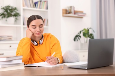 Photo of Student with headphones studying at table indoors