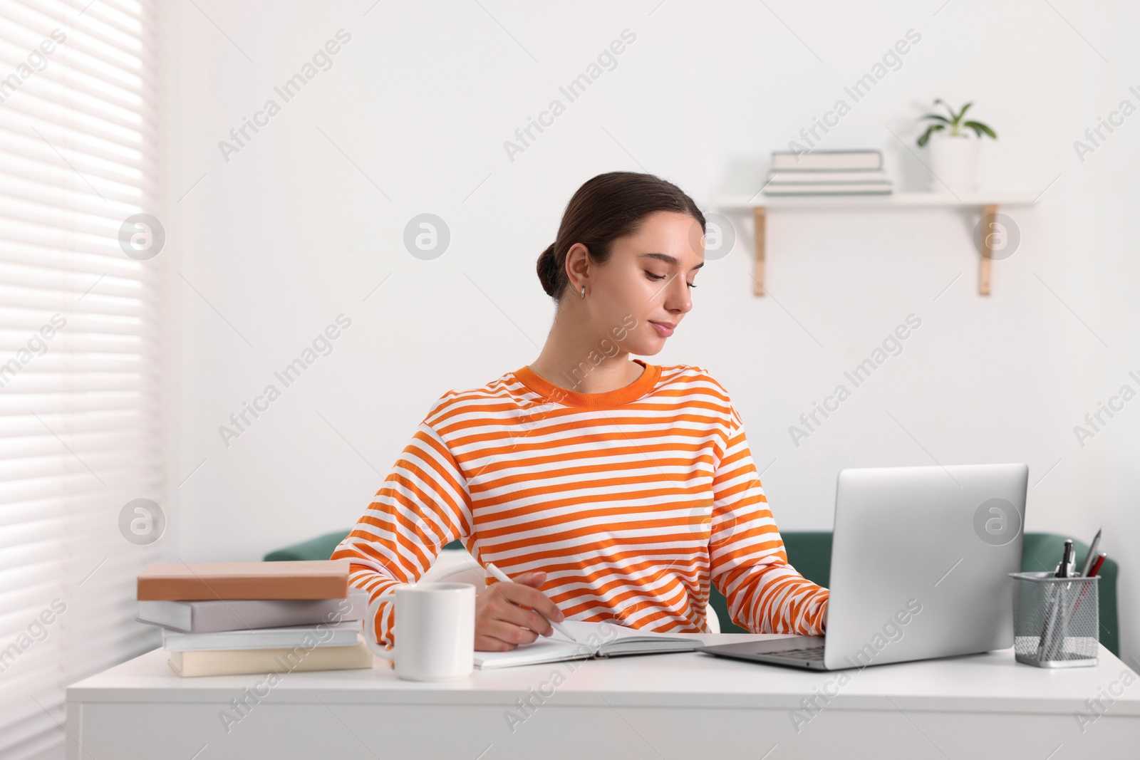 Photo of Student studying with laptop at table indoors