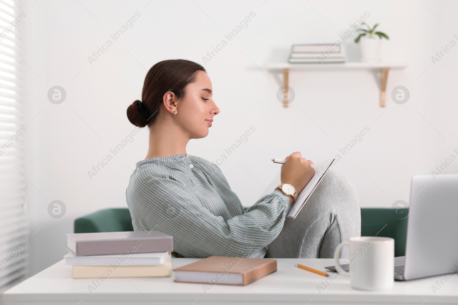 Photo of Student taking notes while studying at home