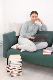 Student in headphones studying with laptop on sofa at home