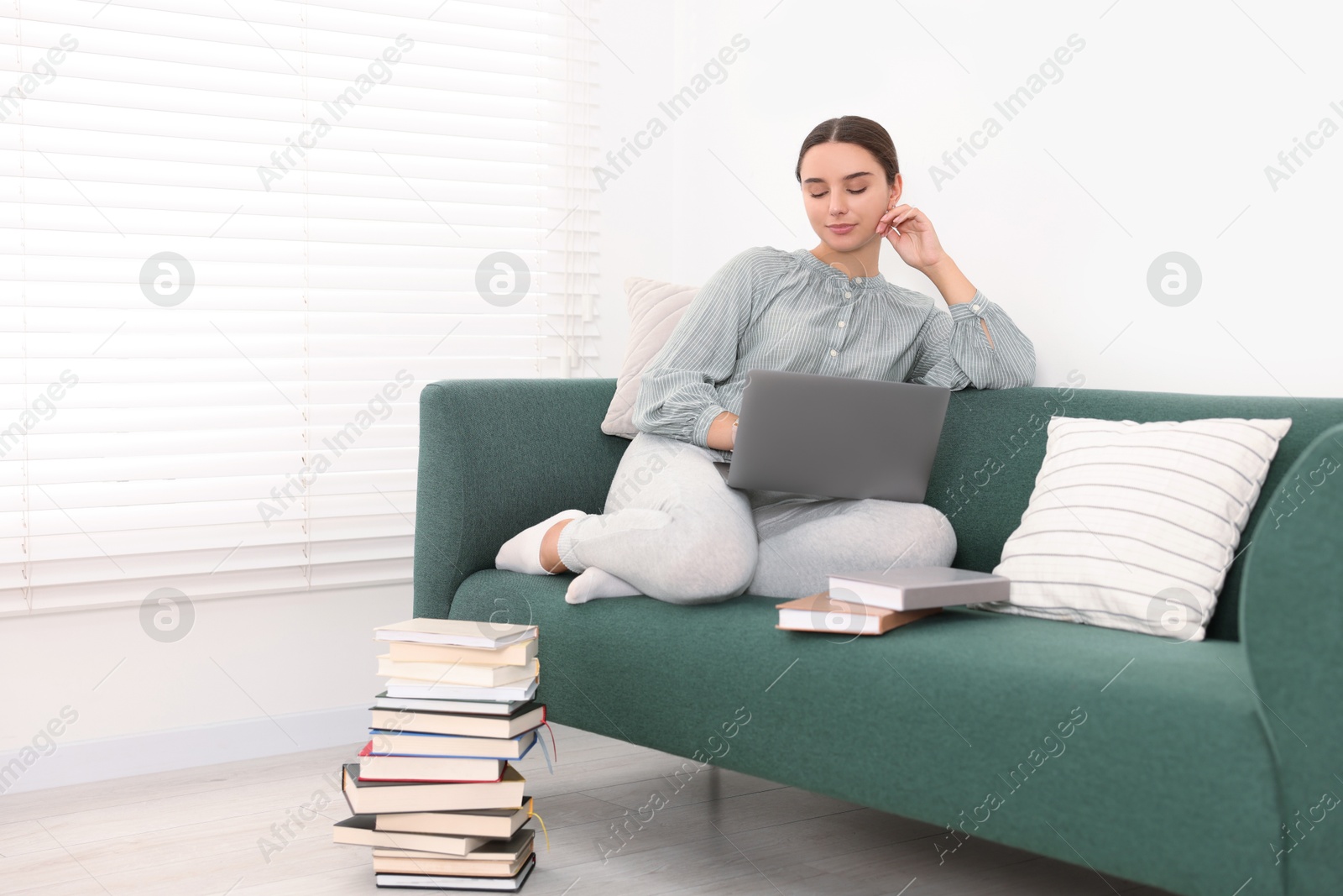 Photo of Student in headphones studying with laptop on sofa at home