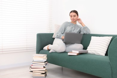 Student in headphones studying with laptop on sofa at home