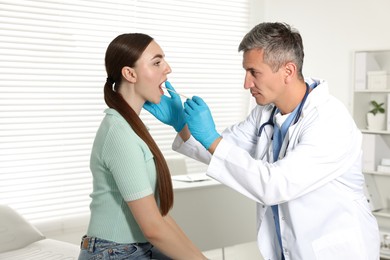 Photo of Doctor examining woman's throat with tongue depressor in clinic