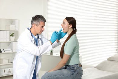 Photo of Doctor examining woman's throat with tongue depressor in clinic