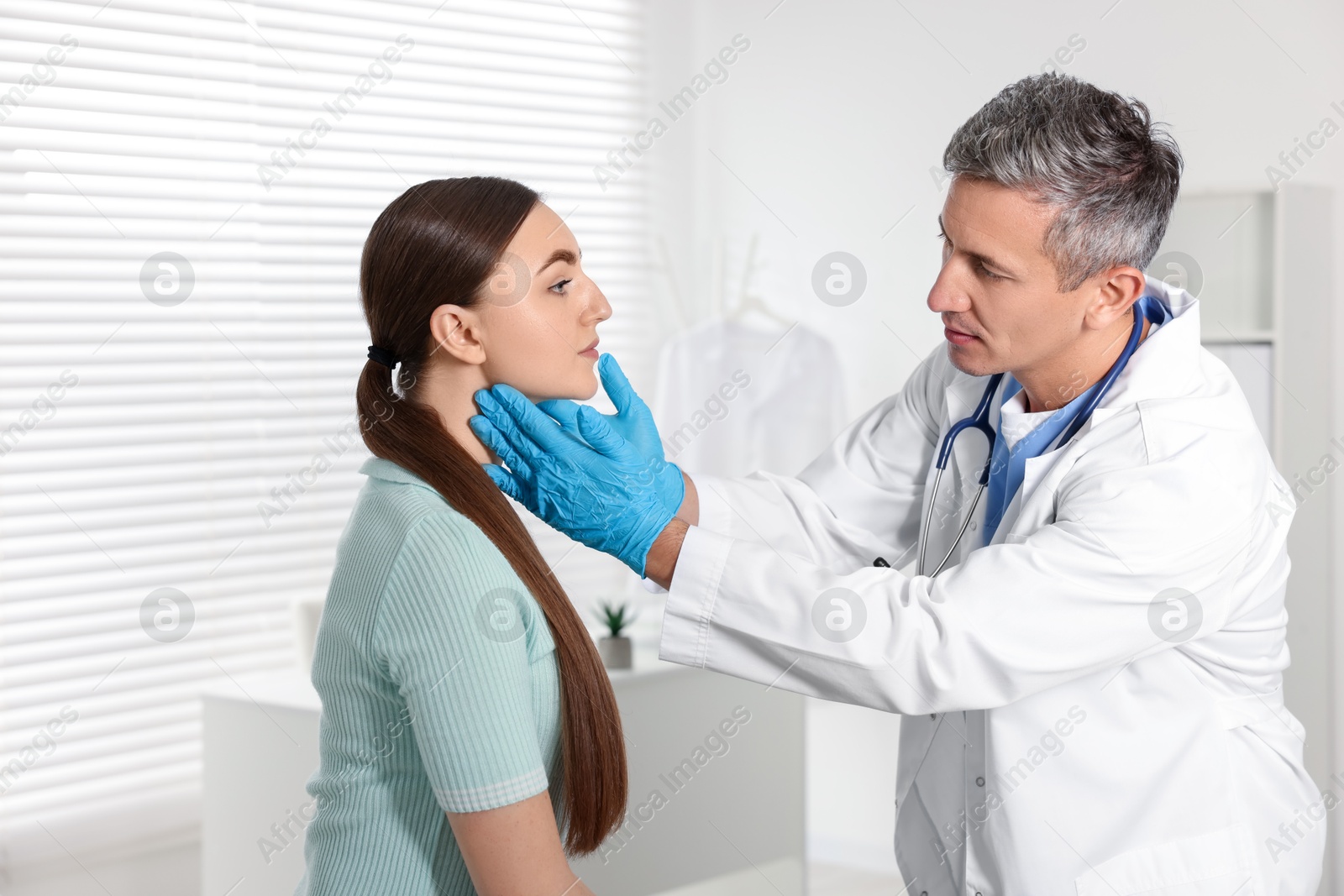 Photo of Doctor examining woman's throat in clinic during appointment