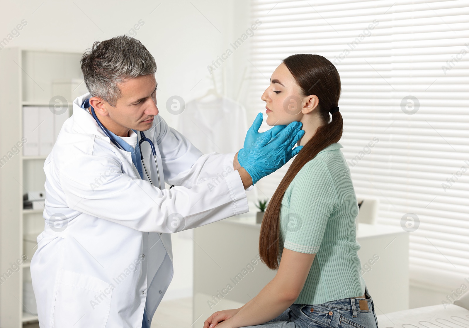 Photo of Doctor examining woman's throat in clinic during appointment