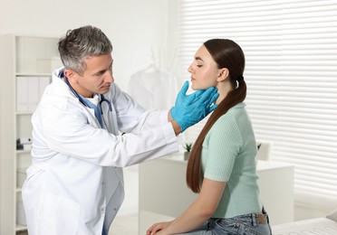 Photo of Doctor examining woman's throat in clinic during appointment