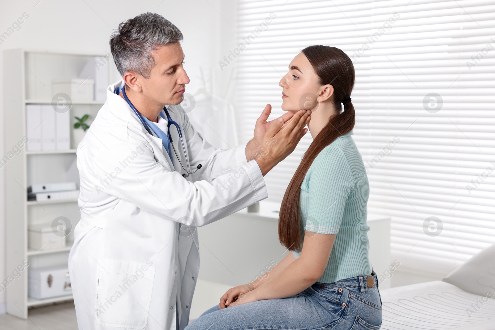 Photo of Doctor examining woman's throat in clinic during appointment