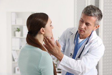 Photo of Doctor examining woman's throat in clinic during appointment