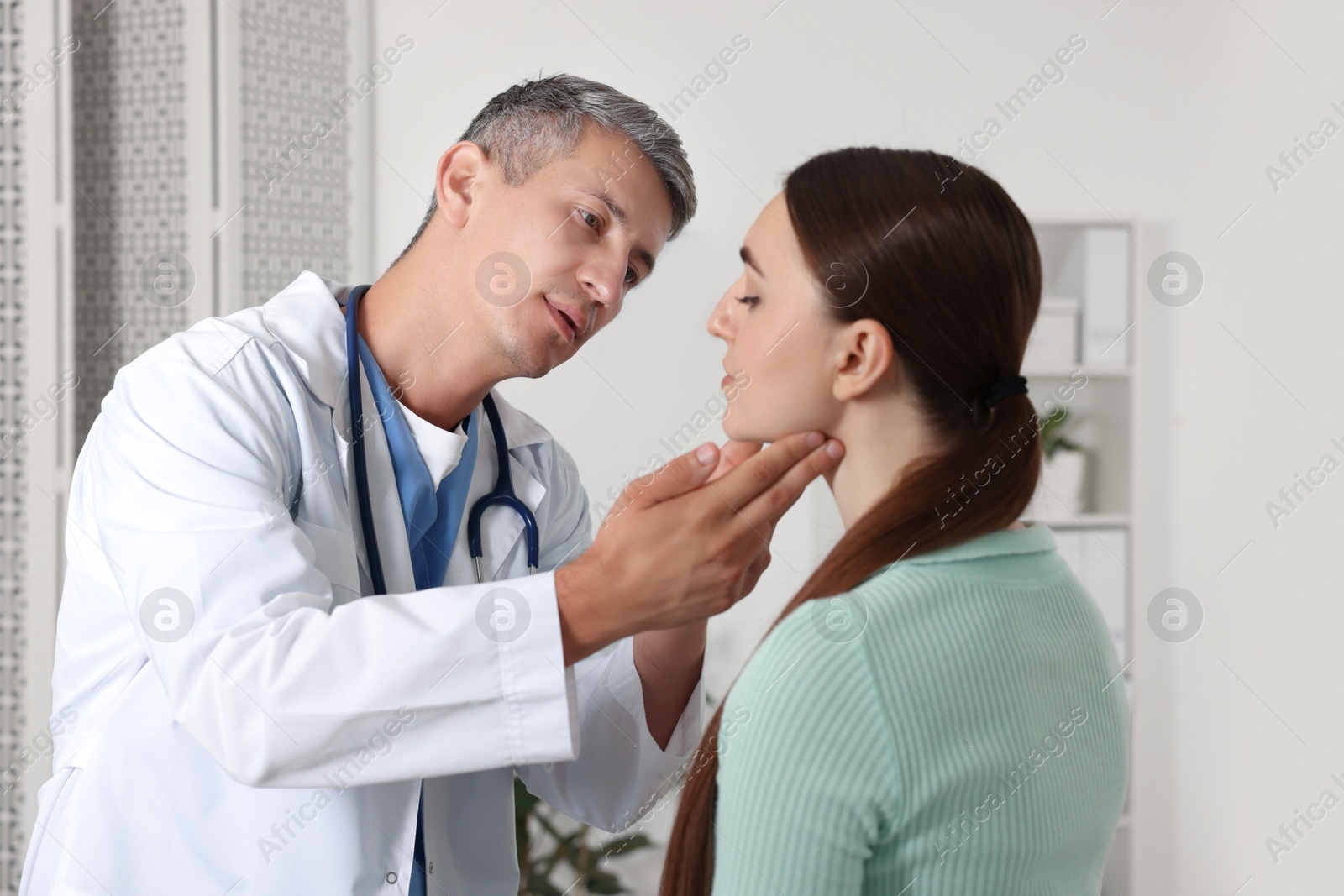 Photo of Doctor examining woman's throat in clinic during appointment