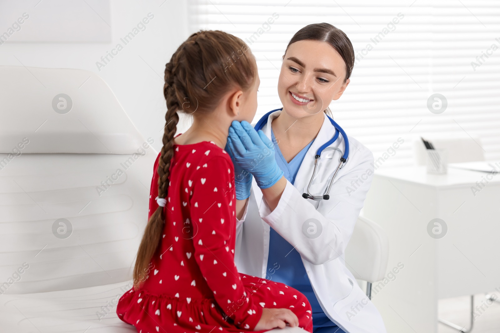 Photo of Doctor examining girl's throat in clinic during appointment