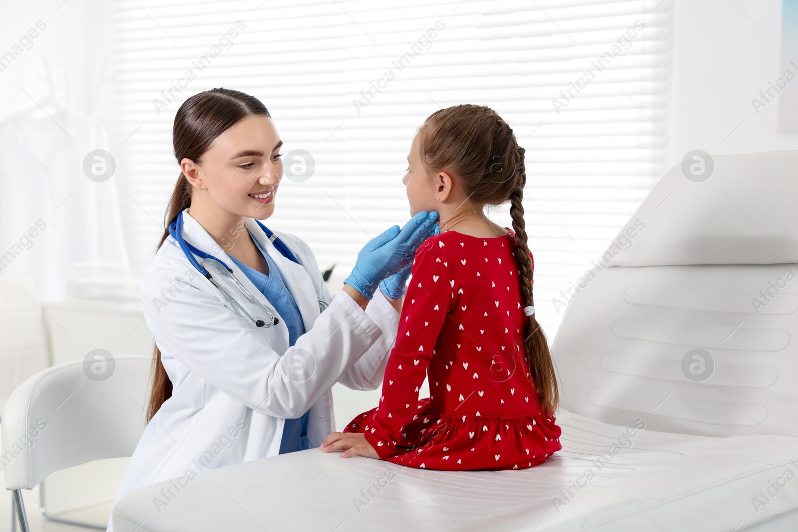 Photo of Doctor examining girl's throat in clinic during appointment