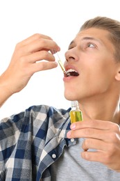 Photo of Young man taking CBD tincture indoors. Herbal extract