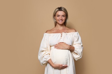 Portrait of beautiful pregnant woman on beige background