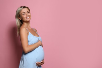 Photo of Portrait of beautiful pregnant woman on pink background, space for text