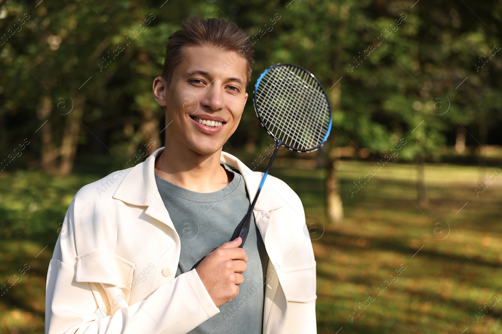 Photo of Happy young man with badminton racket in park