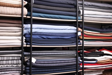 Photo of Many different types of fabric on shelves in professional atelier