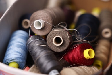 Photo of Many different spools of thread in container, closeup