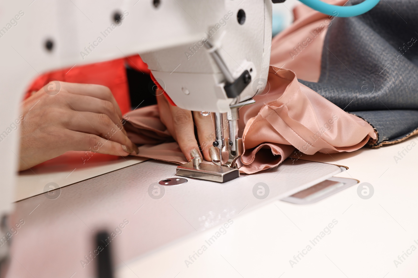 Photo of Woman working with sewing machine in professional workshop, closeup