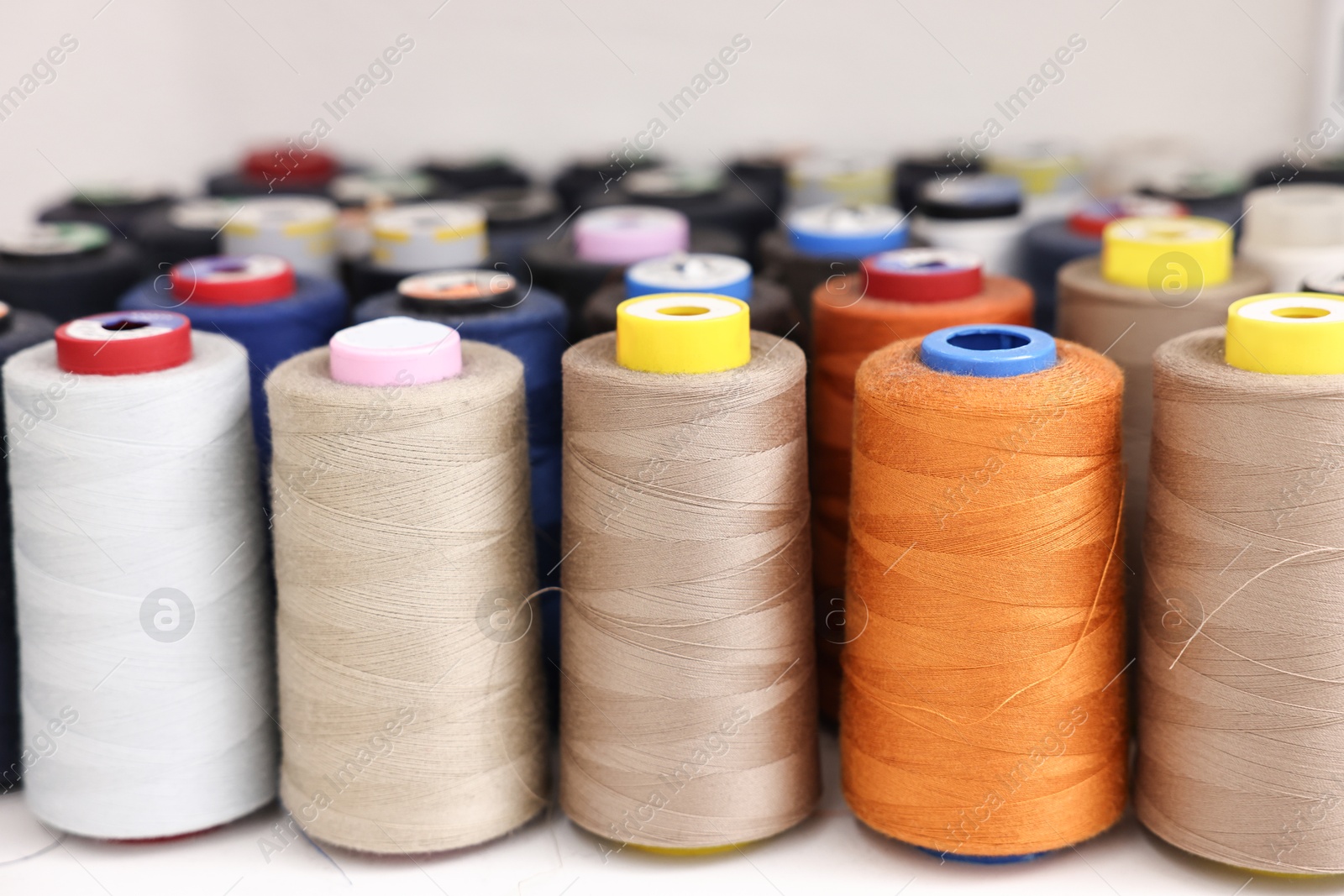 Photo of Many different spools of thread on white shelf in professional workshop