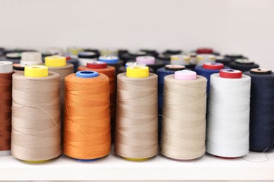 Photo of Many different spools of thread on white shelf in professional workshop